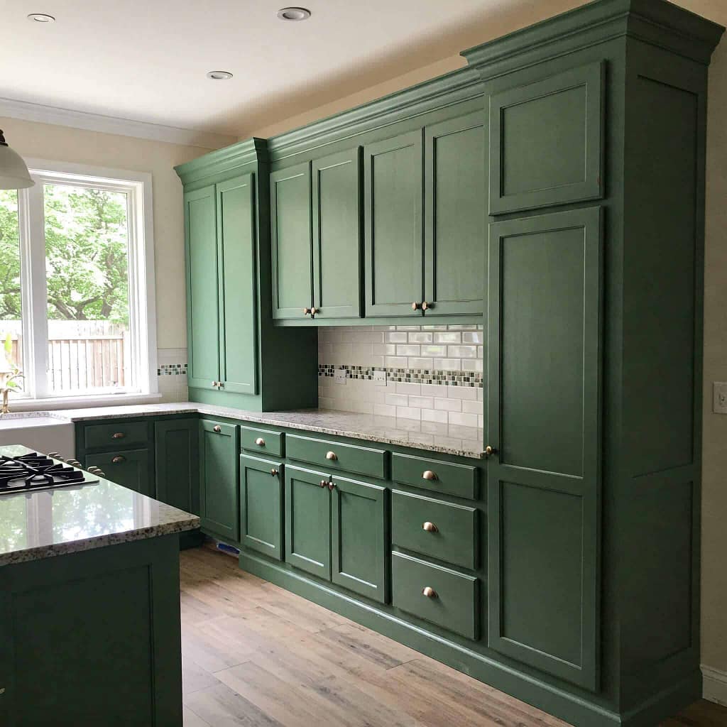Bright green kitchen cabinets with granite countertops and white subway tile backsplash in a modern Portstewart home. Expert interior painting by G&E Interior Painting.