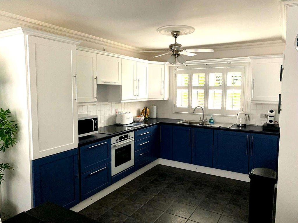 Vibrant blue and white kitchen cabinets in a modern, freshly painted interior with natural light, showcasing expert painting services in Portstewart for home renovations.