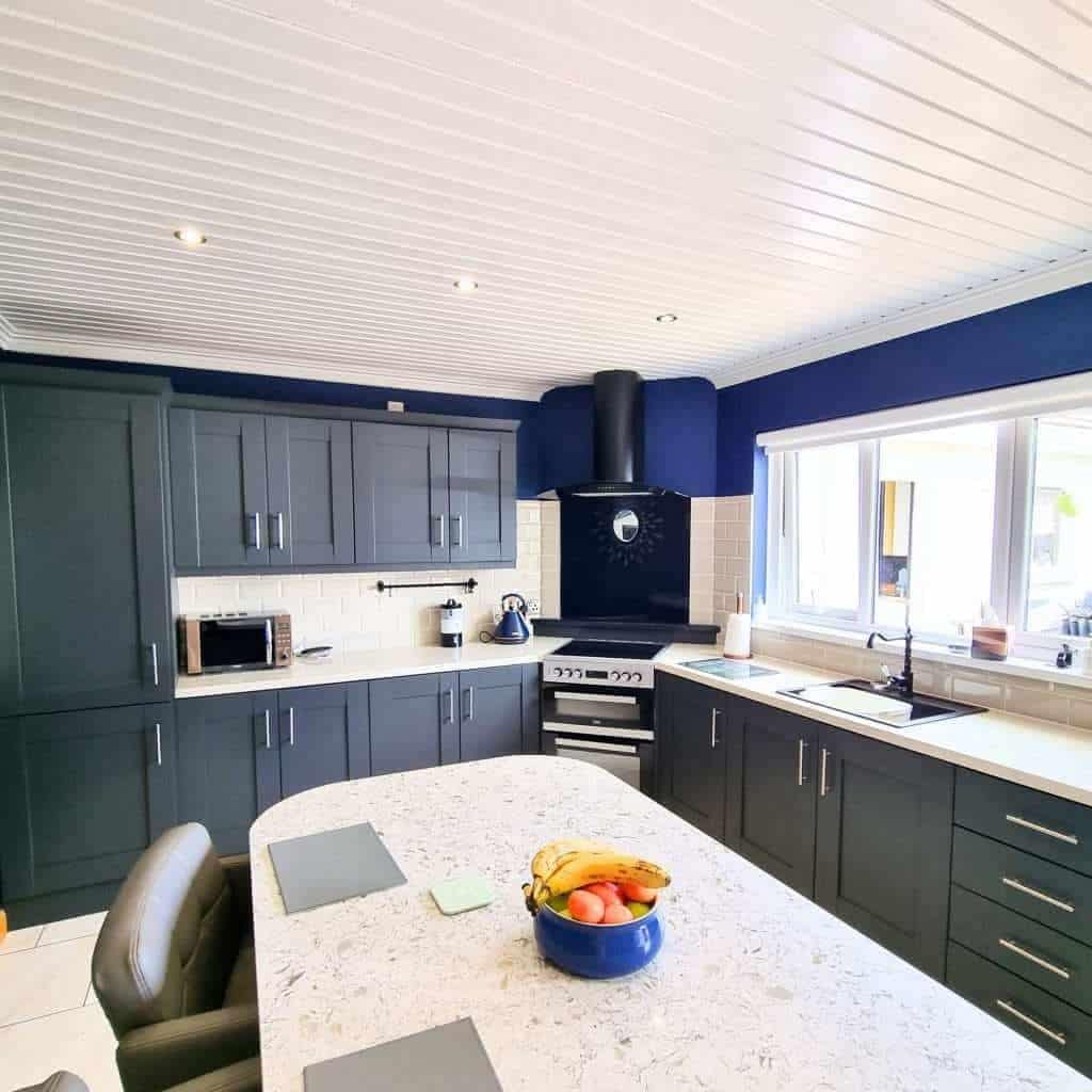 Vibrant navy blue kitchen cabinets with white subway tile backsplash and modern appliances, showcasing professional interior painting services in Portstewart for stylish home upgrades.