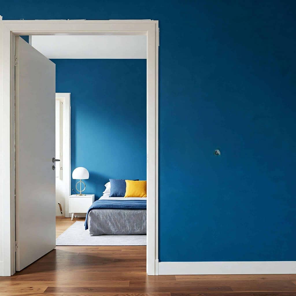 Open door revealing modern blue bedroom interior