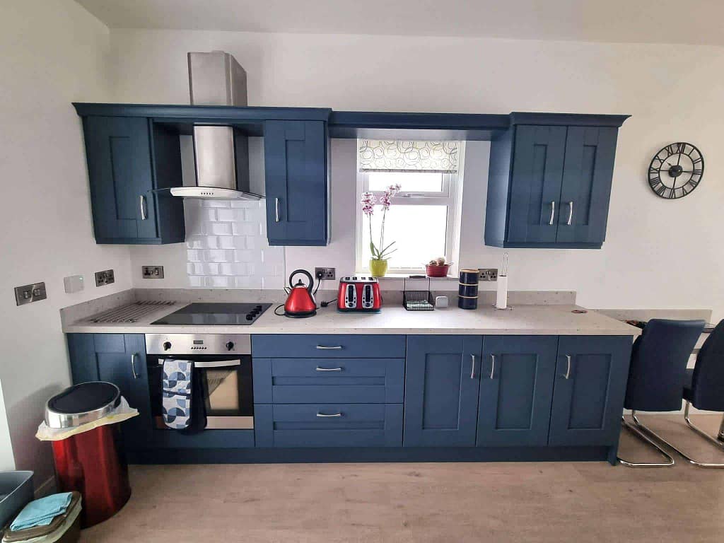 Bright blue kitchen cabinets, modern appliances, and a white subway tile backsplash in a home interior. Expert painting services by G&E Interior Painting in Portstewart highlight the vibrant finish and quality craftsmanship.