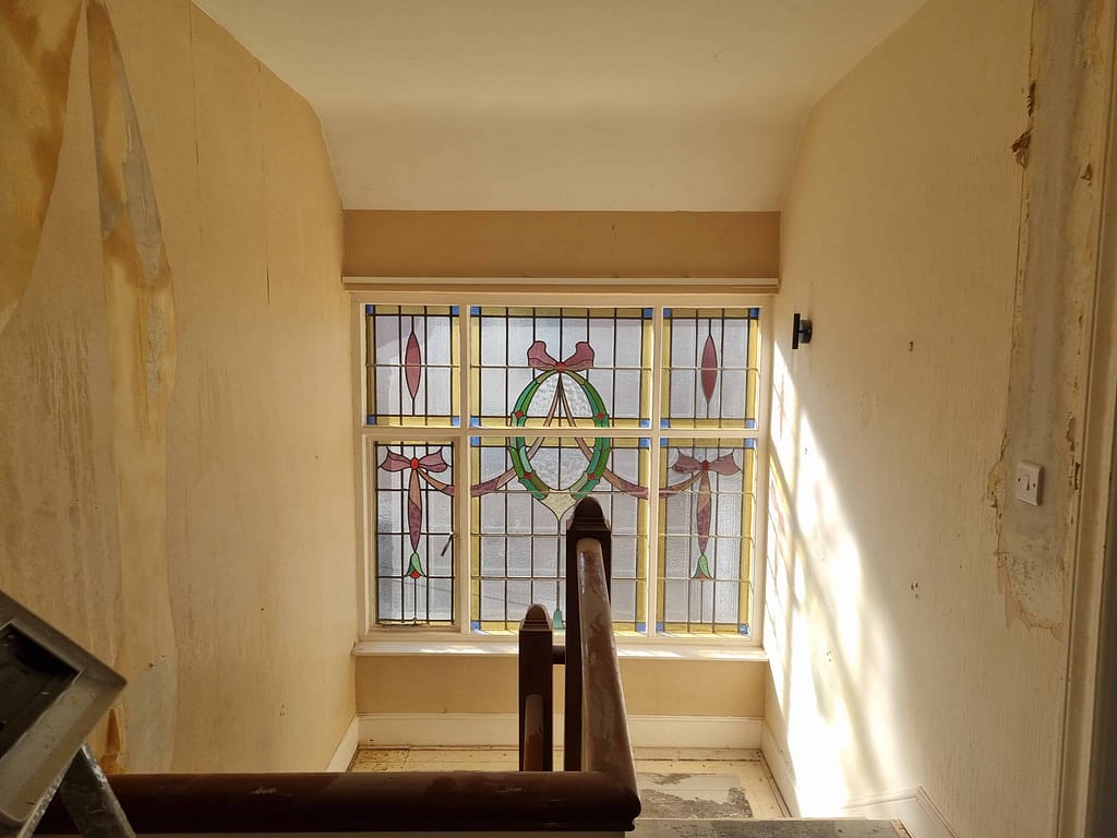 Vintage stained glass window restoration in a historic interior, featuring intricate designs and colorful details, completed by expert painters in Portstewart.