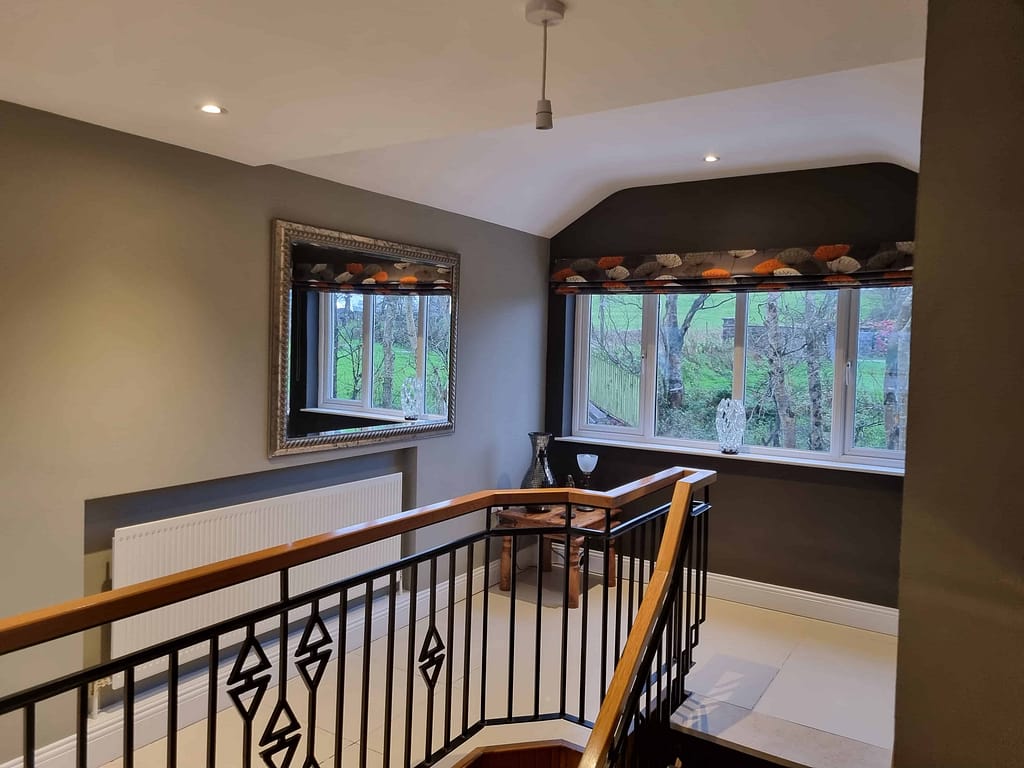 Porch interior with freshly painted walls, large windows with patterned valances, decorative glass vases, and a wooden railing, showcasing expert interior painting services in Portstewart.