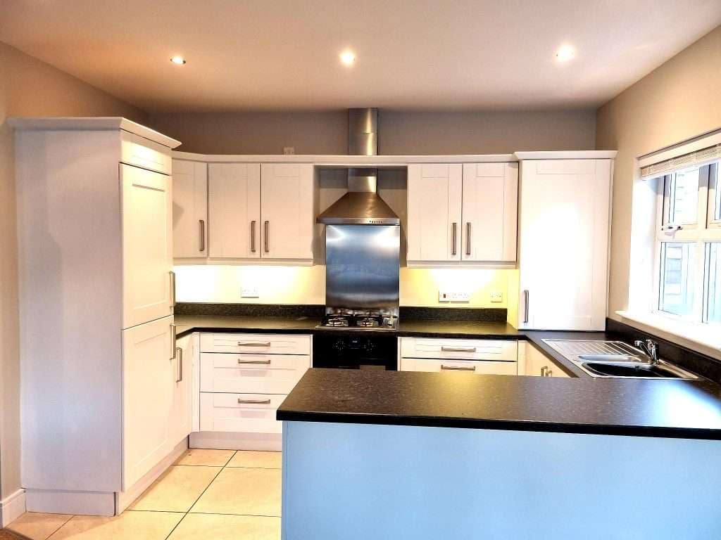 Bright white kitchen cabinets and black countertops featuring professional interior painting services by G&E Interior Painting in Portstewart. Expert painters transforming family homes.