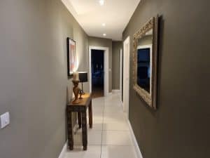 Modern hallway by interior painters Portstewart showing design Modern hallway interior painted with stylish gray tones, featuring decorative wall art, a classic wooden console table, and an ornate framed mirror, showcasing professional interior painting by G&E Interior Painting in Portstewart.
