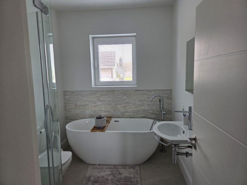Modern bathroom interior with white walls, freestanding bathtub, shower enclosure, and sleek fixtures, expertly painted by G&E Interior Painting in Portstewart.