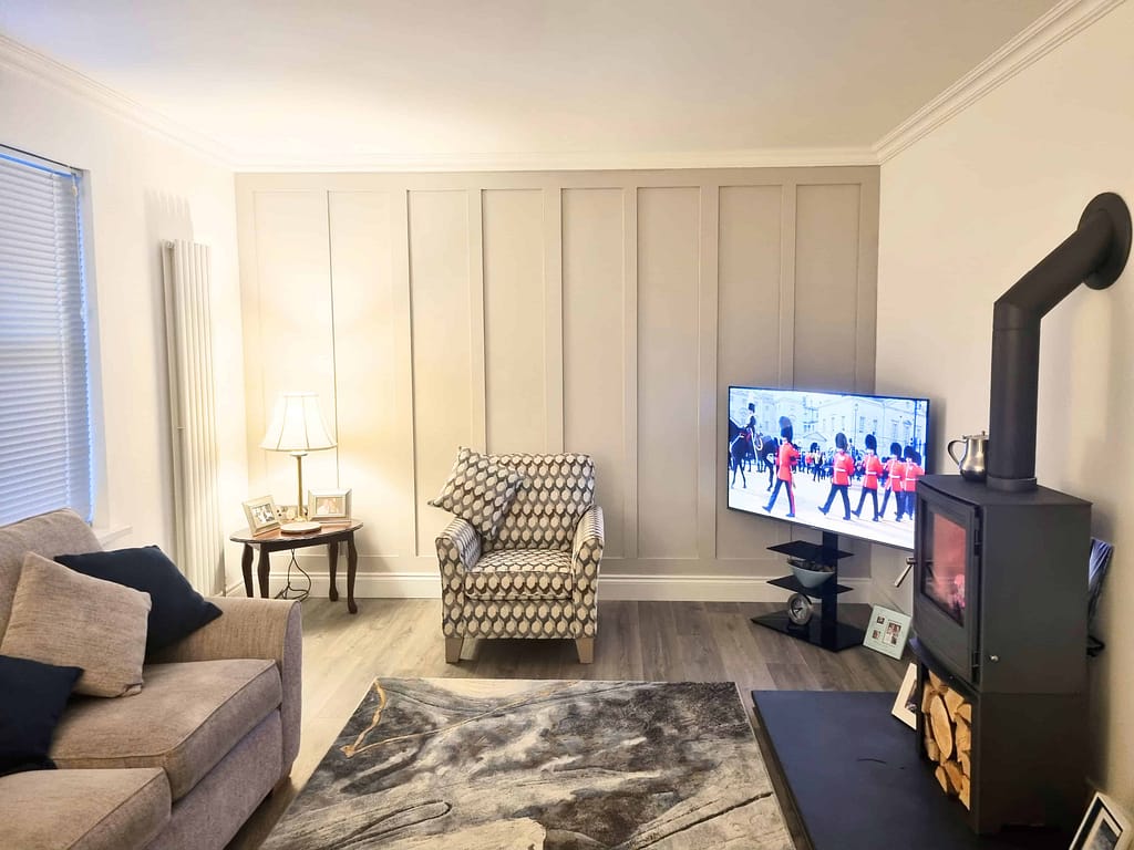 Bright living room interior with freshly painted beige walls, cozy furniture, and a modern fireplace, showcasing expert interior painting services in Portstewart.