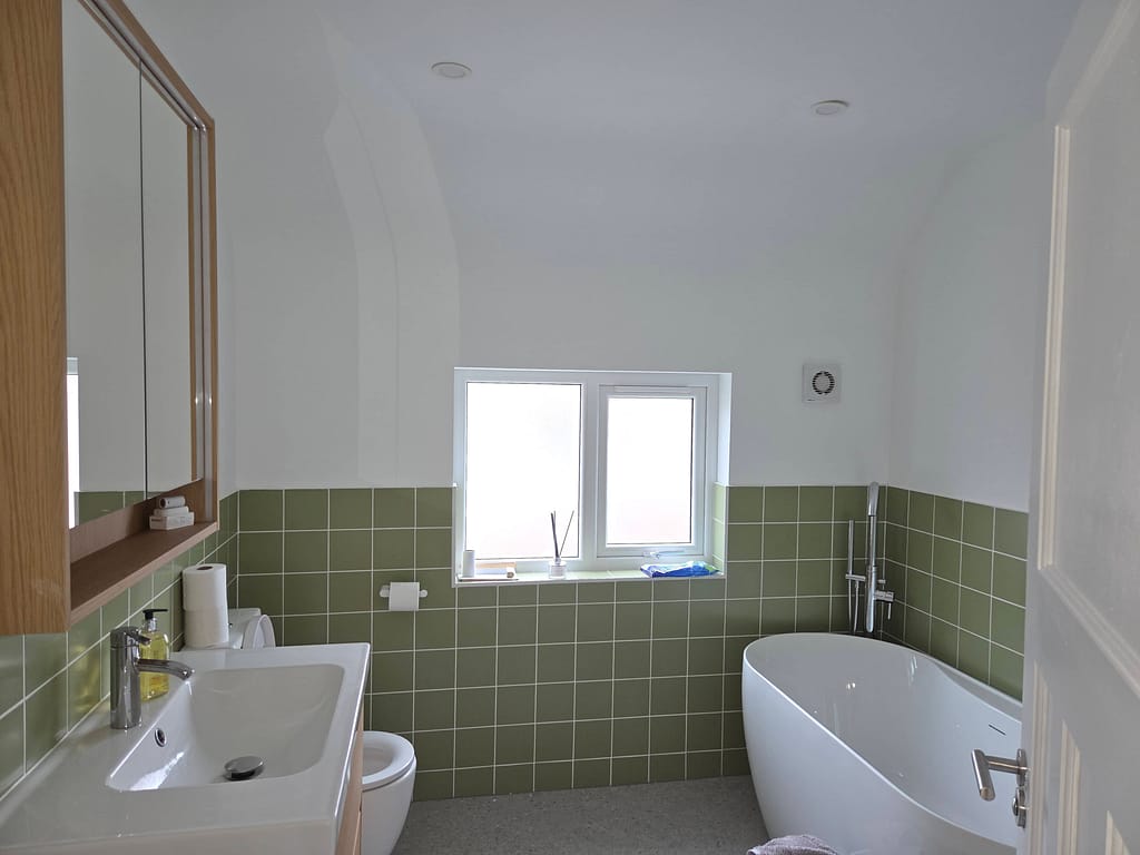 Modern bathroom with green tiled interior walls in a castlerock hoildayhome 