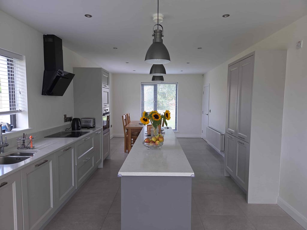 Bright modern kitchen with white cabinetry, grey countertops, and stainless steel appliances in a contemporary interior renovation in Portstewart.