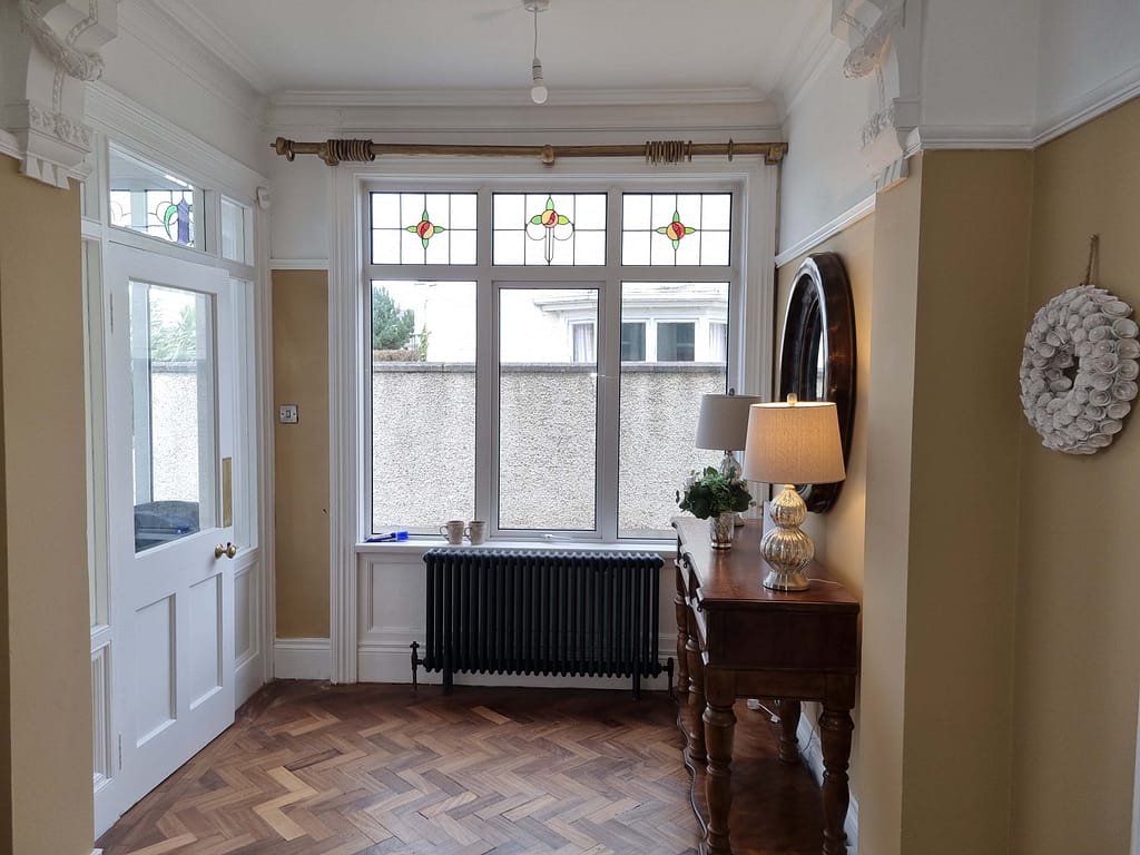  Interior painting and decorating in a traditional hallway with neutral walls, white woodwork and parquet flooring.