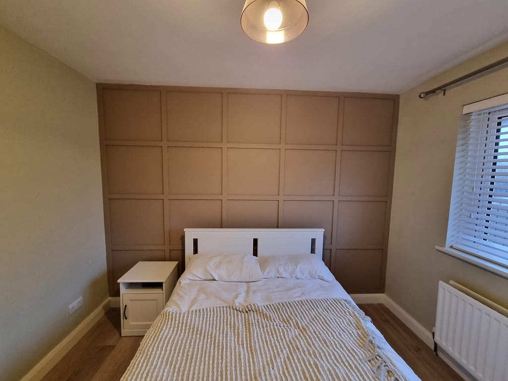 Bedroom with beige feature wall panelling and neutral interior paintwork in Portstewart.