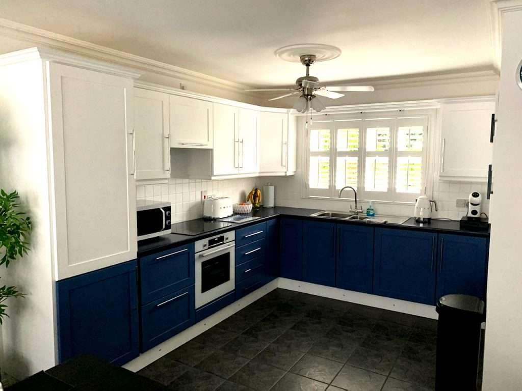 Vibrant blue and white kitchen cabinets in a modern, freshly painted interior with natural light, showcasing expert painting services in Portstewart for home renovations.