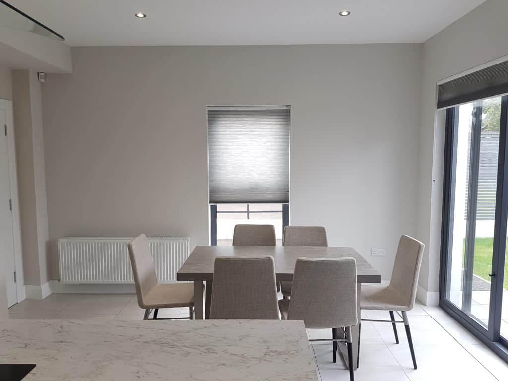 Modern dining room with neutral painted walls and large sliding glass doors, showcasing professional interior painting by G&E Interior Painting in Portstewart, creating a stylish and bright living space.