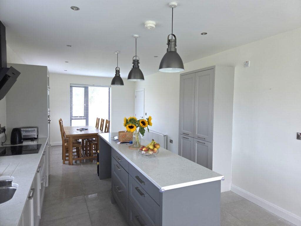 Bright modern kitchen interior featuring light gray cabinetry, sleek white countertops, and stylish pendant lighting, showcasing professional interior painting services in Ports.